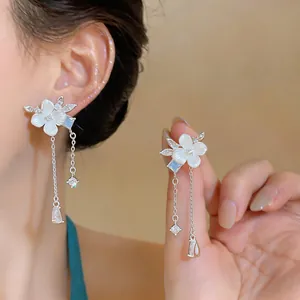 Detalle de elegantes pendientes de flor con circonitas y borlas para un look refinado