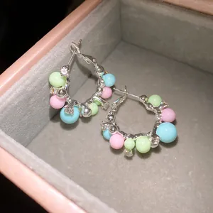 Close-up detail of colorful pastel bead hoop earrings with crystal accents in a box