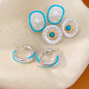 Detail of silver zircon earrings set with turquoise accents including oval hollow and flower studs
