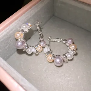 Detail shot of elegant silver hoop earrings with multicolored pearls and rhinestones.