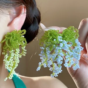 Close-up of green and blue glass beaded tassel earrings in a French pastoral style