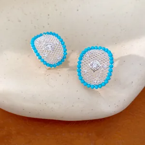 Detailed view of oval zircon stud earrings with intricate hollow silver latticework.