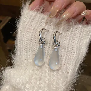 Detail view of silver C-shaped earrings featuring translucent resin water drop pendants