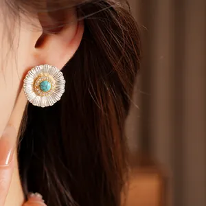 Silver flower stud earrings with turquoise center and zircon accents worn on ear