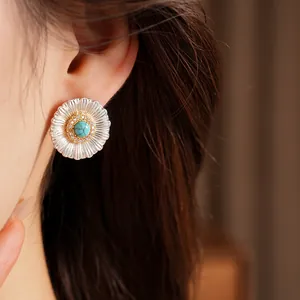 Close-up detail of a silver sunburst earring featuring a turquoise stone and zircons