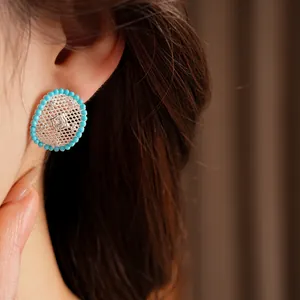 Close-up of elegant turquoise bead oval earrings with silver hollow mesh detail