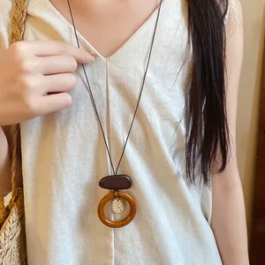 Detail shot of a retro wooden ring pendant necklace paired with natural linen attire