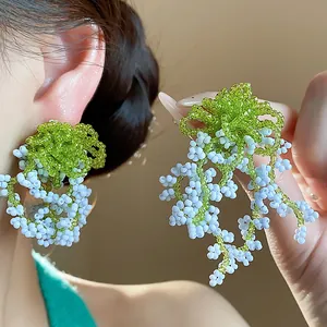Close-up of handmade green and blue glass beaded tassel earrings with silver needles