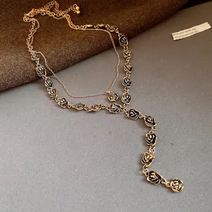 Dettaglio ravvicinato di una collana dorata a due strati con delicati ciondoli a rosa