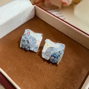 Detailed view of blue crushed ice zircon stud earrings in a luxury brown gift jewelry box