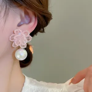 Primo piano di un orecchino a fiore in cristallo rosa con un grande pendente di perla