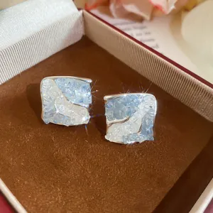 Close-up detail of blue crushed ice zircon stud earrings inside a luxury brown jewelry box