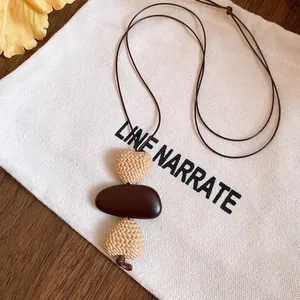 Close-up of an ethnic style necklace with heart-shaped and pebble pendants on a bag