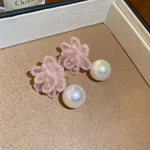 Dettaglio di eleganti orecchini a fiore di perline rosa fatti a mano con perla rotonda.