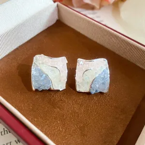 Close-up of Korean style square stud earrings with blue crushed ice zircon stones.