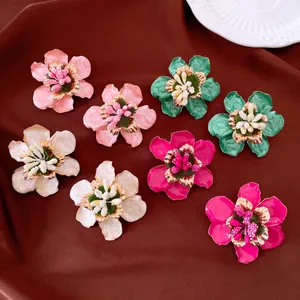 Detailansicht von farbenfrohen Emaille-Blumenohrringen auf elegantem braunem Stoff