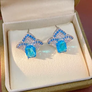Detailed view of elegant blue and white zircon earrings in a jewelry box with fan-shaped design.