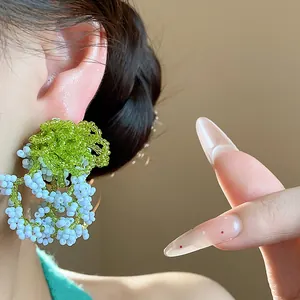 Detailed macro shot of French pastoral style green and blue glass beaded earrings.