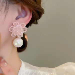 Dettaglio di eleganti orecchini a fiore in cristallo rosa con una grande perla bianca