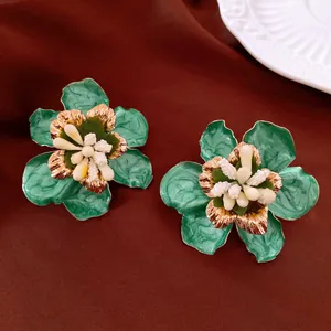 Nahaufnahme von grünen Blumenohrringen mit Goldakzenten und weißen Stempeldetails.