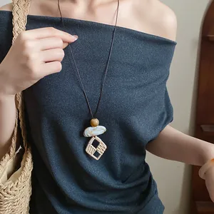 Detail shot of vintage ethnic long necklace with a woven geometric pendant on model