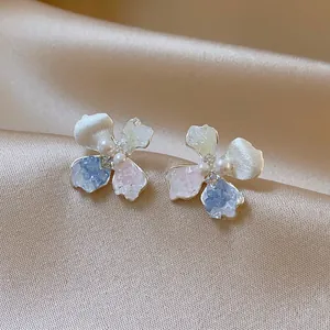 Close-up of elegant flower earrings with blue and pink crushed ice textures and central pearl