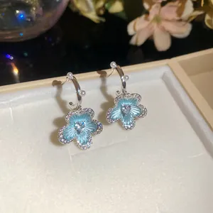 Detailed macro shot of elegant light blue flower earrings featuring zircon and pearls