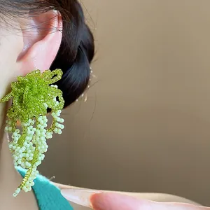 Close-up of French pastoral green beaded tassel earrings with silver needle detail