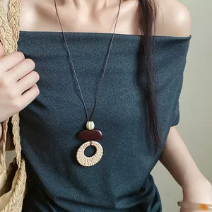 Detail of ethnic style long necklace with woven ring pendant and pebble-like beads.