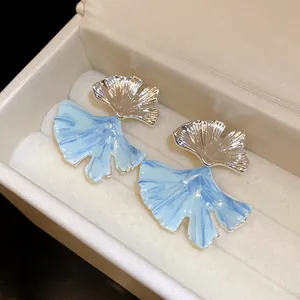 Detailed macro view of blue marble texture ginkgo leaf stud earrings in jewelry box