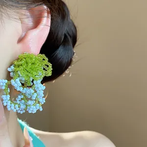 Detailed view of French garden style green and light blue beaded cluster earrings