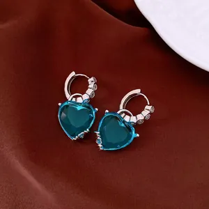 Close-up of blue heart-shaped zircon earrings on elegant brown satin