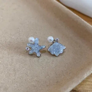 Detail view of light blue crushed ice starfish and shell earrings with pearls