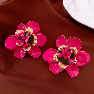 Nahaufnahme von pinkfarbenen Emaille-Blumenohrringen mit goldenen Details am Blütenstempel