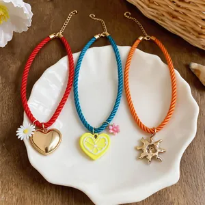 Detailed view of three colorful rope necklaces with heart, lemon, and sun pendants.