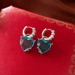 Detailed close-up of vintage heart blue zircon hoop earrings on red box