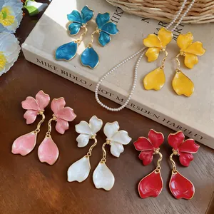 Macro view of colorful flower earrings with enamel petals and gold drop accents
