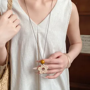 Detail view of ethnic style long necklace with woven flower pendant and wooden bead
