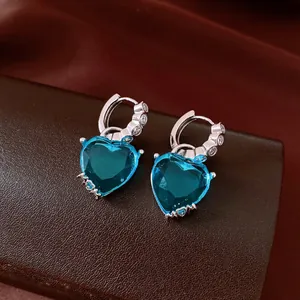 Close-up of vintage heart-shaped blue zircon hoop earrings on leather background