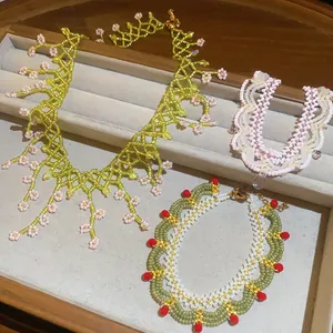 Detailed view of three unique handmade glass beaded necklaces featuring floral and wavy designs