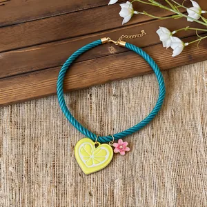 Close-up of a turquoise twisted rope necklace with a yellow lemon heart pendant.