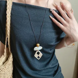 Vintage bohemian long necklace with irregular stone and woven pendants on dark top