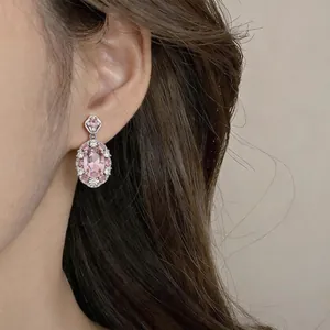Nahaufnahme eines vintage-rosa ovalen Zirkon-Ohrrings, getragen von einem eleganten Modell