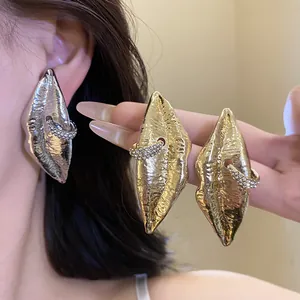 Detailed view of exaggerated lip-shaped earrings with crystal-encrusted rings in gold and silver.