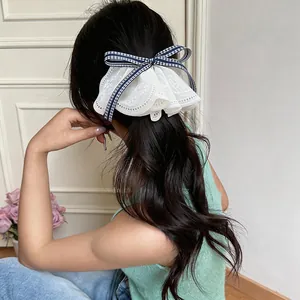 Detailed macro view of white lace bow hair clip with navy gingham ribbon on model hair