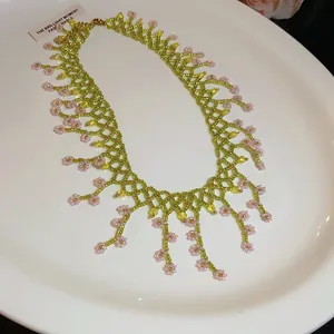 Close-up of handmade lime green beaded necklace with delicate pink flower charms.