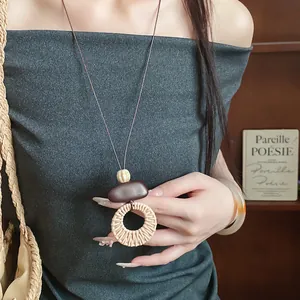 Close-up of bohemian style woven ring pendant necklace worn by model