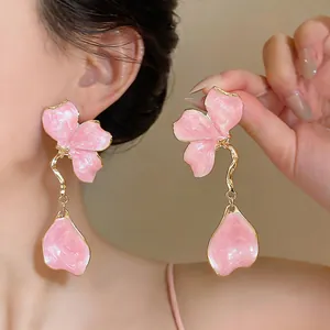 Elegant pink enamel flower dangle earrings with gold-tone accents shown on a model.