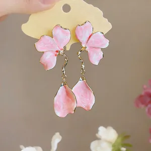 Close-up of pink enamel flower drop earrings with wavy stems and petal-shaped dangles.