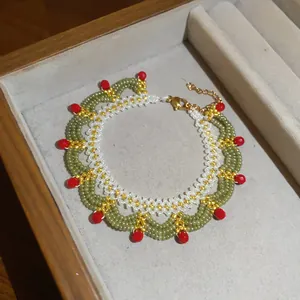 Detailed macro shot of a handmade green and white beaded lace necklace with red accents